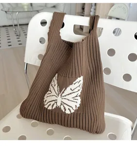 Brown knitted handbag detail shot featuring a stylish white woven butterfly pattern.