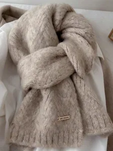 Detalle de la bufanda de punto suave con textura acogedora y pequeña etiqueta metálica.