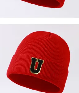 Red knitted beanie hat detail, winter warm wool cap with black gold letter U patch.