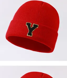 Detailed shot of a vibrant red knitted beanie hat featuring a stylish black and gold letter Y patch.