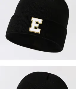 Close-up detail of black knitted beanie hat featuring a white letter E patch, stylish streetwear.