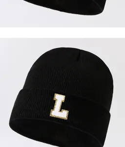 Black knitted beanie hat detail, warm winter knitted cap with white gold letter L patch.