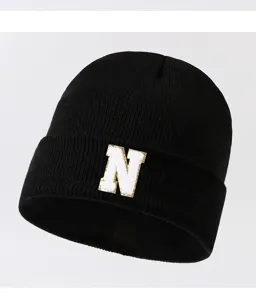 Detailed view of the black knit beanie featuring a stylish gold and white letter N patch.