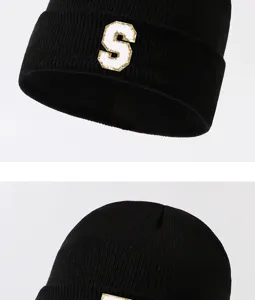 Detailed close-up shot of black winter knit beanie featuring a white letter S patch.