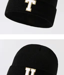 Black knit beanie hat with stylish varsity letter patches, warm and cozy winter streetwear.
