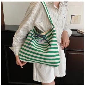 Green and white striped canvas tote bag detail view, casual shoulder bag with bow accent.