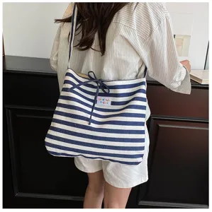 Close-up detail of casual blue and white striped canvas shoulder tote bag with drawstring.