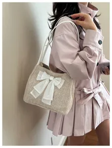 Stylish straw shoulder bag with a white bow, worn on shoulder showing elegant daily detail.
