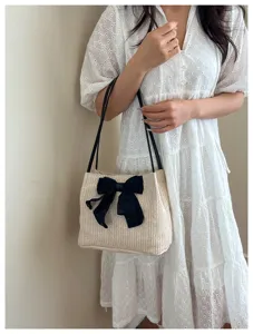 Detailed view of women straw woven shoulder tote bag featuring elegant black bow accent.