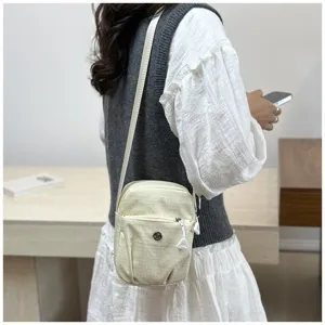 Detail view of mini crossbody mobile phone bag worn by model, lightweight and practical.