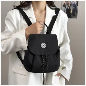 Détail de sac à dos de voyage casual en nylon noir avec cordon et badge chic.