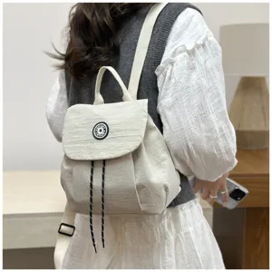 Vue détaillée du sac à dos élégant en toile beige avec cordon de serrage et design à rabat.