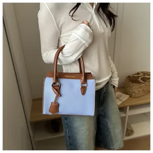 Detail view of the stylish color-block handbag in light blue and brown, showcasing texture.