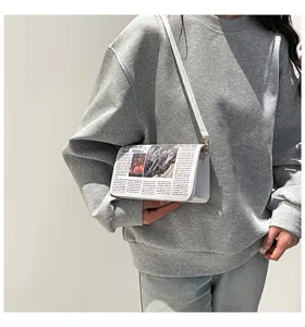Vue détaillée du sac à bandoulière blanc imprimé journal avec une fine lanière.