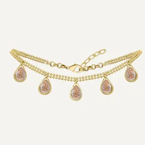 Gros plan détaillé de l'élégant collier doré double rang aux pendentifs en cristal en goutte.