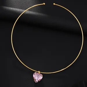 Primo piano di una collana girocollo in metallo dorato con ciondolo in cristallo rosa a cuore.