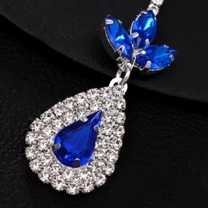 Close-up detail of a stunning blue rhinestone teardrop forehead pendant and crystal cluster.