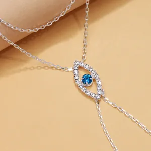 Primer plano de cadena de mano de mal de ojo plateada con brillantes estrases azules.