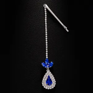 Closeup view of sparkly rhinestone brow pendant featuring blue crystal drops and clip.