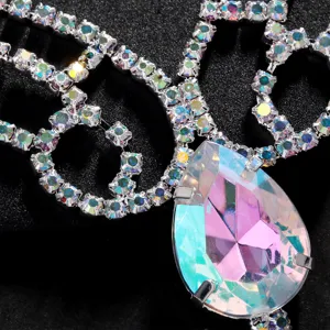 Close-up of rhinestone face mask detail with iridescent crystal pendant and sparkling silver chains.