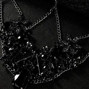 Dettaglio in primo piano di lussuosa maschera in strass neri con catene argentate.
