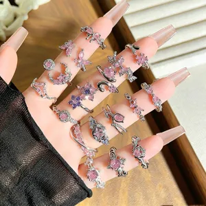 Detailaufnahme von Y2K rosa Zirkonringen mit niedlichen Schmetterling- und Blumenmotiven.