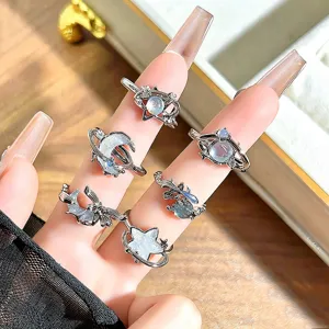 Close-up detail of sweet style enamel planet and star open rings worn on manicured fingers.