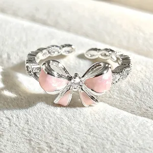 Close-up of a sweet pink enamel bow open ring with sparkling cubic zirconia, delicate design.