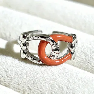 Close-up of a sweet style silver-plated enamel open ring with coral red detail, chic accessory.