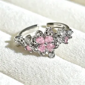 Close-up detail of silver open ring featuring pink heart-shaped stones in flower clover shape.