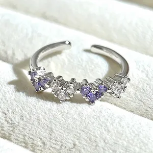 Detailed close-up of a silver-toned open ring featuring alternating purple and clear heart stones.