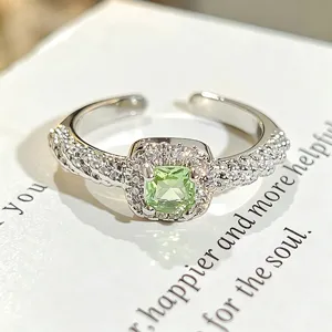 Primer plano detallado de un elegante anillo abierto de plata con circón verde claro y pavé.