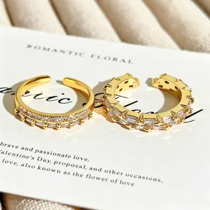 Primer plano de anillos abiertos apilables dorados con circonitas baguette y redondas brillantes.