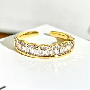 Vista detallada de un anillo abierto dorado con circonitas baguette y diamantes redondos para apilar.