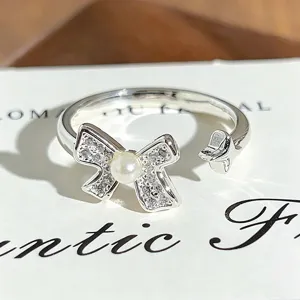 Detail shot of silver open ring featuring rhinestone bow with pearl and star design.