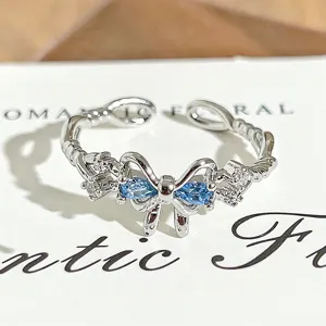 Close-up detail of silver open ring featuring a sparkling blue bow design with cubic zirconia.
