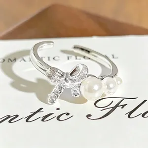 Adjustable silver ring featuring a sparkling rhinestone bow and elegant pearl embellishments for women.