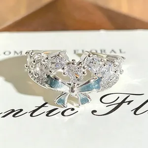 Close-up detail of silver open ring with sparkly cubic zirconia and light blue enamel bow.