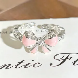 Silver open ring featuring a pink enamel bow and sparkling zircon stones for stylish wear.