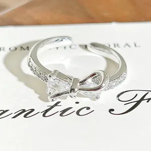 Close-up of silver bow zircon open ring, delicate crystal details and polished finish.