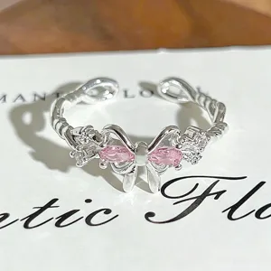 Detailed close-up of a silver open ring with a sparkling pink zircon bow and crystal accents.