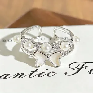 Detailed close-up of a silver open ring featuring pearls, sparkling zircon, and a cute bow.