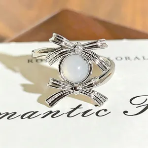 Close-up detail shot of the silver bow ring featuring sparkling zircon and milky center stone.