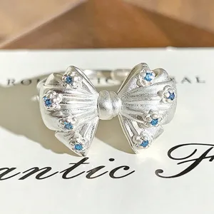 Detailed shot of a silver bow open ring sparkling with blue cubic zirconia stones.