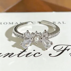 Detailed close-up view of a sparkling zircon and pearl bow open ring with exquisite design.