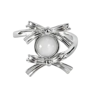 Silver bow ring with central white stone, adjustable open band, delicate fashion jewelry detail.