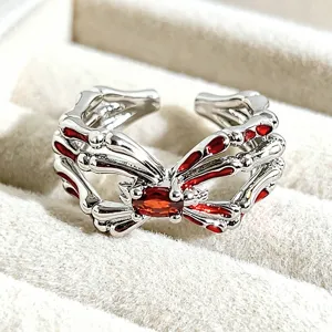 Silver tone gothic bone shape open ring with red enamel and central crystal stone detail.