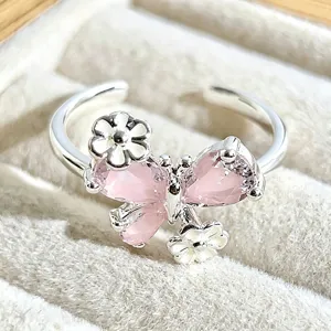 Close-up detail of sweet pink butterfly crystal and white enamel ring, premium stacking jewelry.