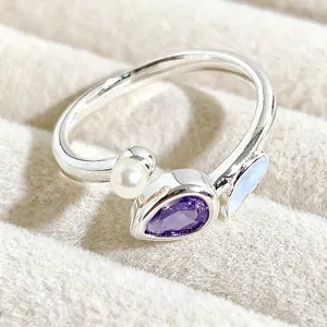 Detailed close-up of a sweet open ring featuring a pearl, purple gemstone, and enamel accent.