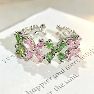 Anillo abierto plateado con circonitas verdes y rosas dispuestas en un elegante diseño floral.